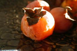 Some ripe persimmons in a bowl.